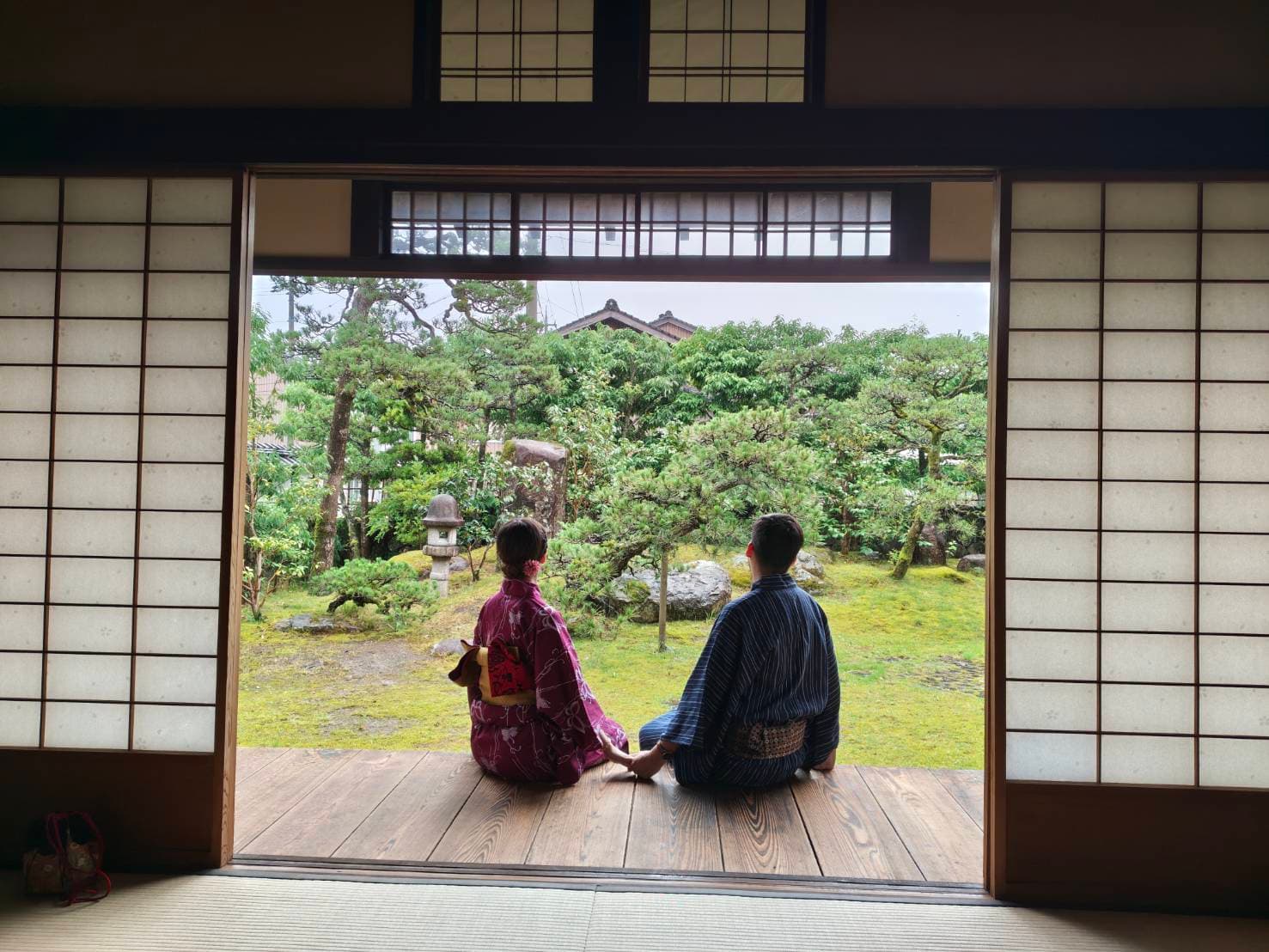 町家の縁側から日本庭園を眺めるふたり